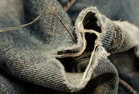 Hole in jeans. Needle with thread for darning jeans. Tools for work dressmake Stock Photos