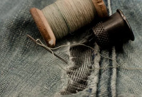 Hole in jeans. Needle with thread for darning jeans. Tools for work dressmake Stock Photos