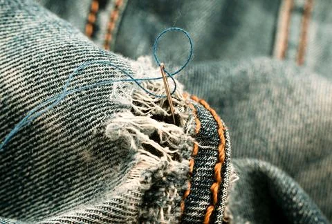 Hole in jeans. Needle with thread for darning jeans. Tools for work dressmake 写真素材