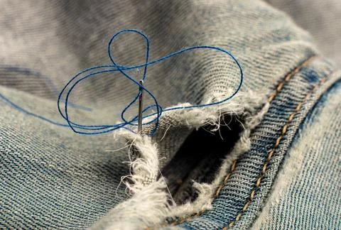 Hole in jeans. Needle with thread for darning jeans. Tools for work dressmake 스톡 사진