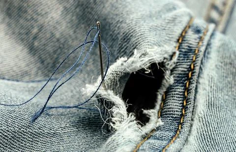 Hole in jeans. Needle with thread for darning jeans. Tools for work dressmake 写真素材
