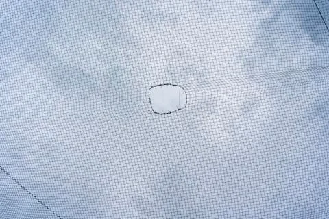 A hole in a net with the sky as a background. Stock Photos