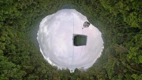Hole Planet Effect Framing Cable Car Above Deep Forest Basin with Dramatic Cloud Vídeos de archivo 323478932