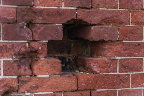 A hole in the red brick wall. A cross in a brick wall The dilapidated brick.. Stock Photos