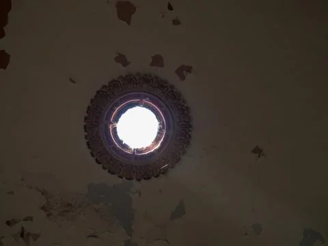 A hole with a stucco pattern in the old ceiling with cracks in the paint thro Foto stock