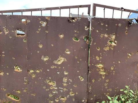Holes on the gate from the explosion of the projectile. A trace on the fenc.. Stock Photos