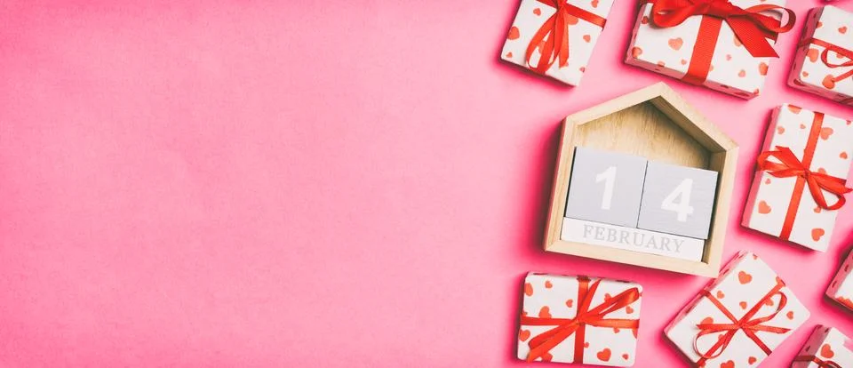 Holiday composition of gift boxes with red hearts and wooden calendar on colo Stock Photos