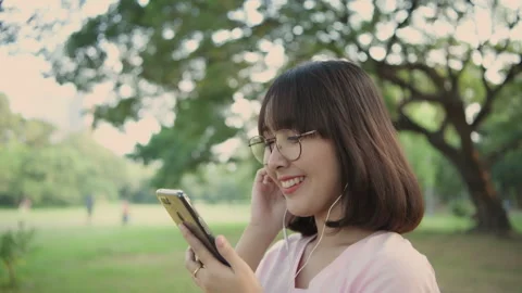 Holiday concept of 4k Resolution. Asian woman listening to music in the garde Stock Footage 334970075