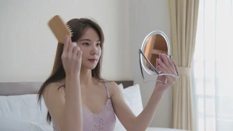 Holiday concept of 4k Resolution. Young Asian woman combing her hair in the b Stock Footage 146288526
