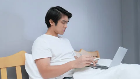 Holiday concept of 4k Resolution. Young Asian man working in the bedroom. tak Stock Footage 213468337