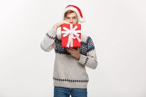Holiday Concept - young handsome man hiding himself behind present. Stock Photos