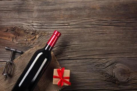 Holiday Dinner setting with red wine and gift on rustic wood in flat lay view Stock Photos