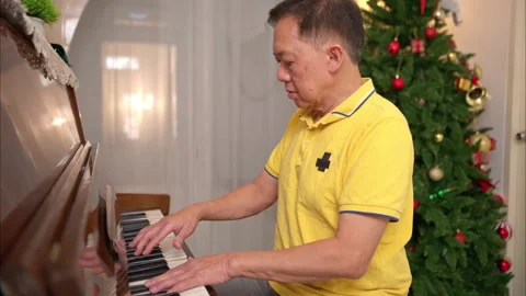 On a holiday, an elderly man enjoys singing and playing the piano at home Stock Footage 319535922