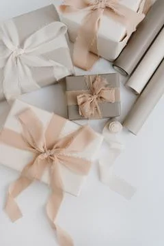 Holiday gift boxes packaging process. Beautiful beige colour gifts with ribbo Stock Photos
