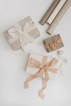 Holiday gift boxes packaging process. Beautiful beige colour gifts with ribbo Stock Photos