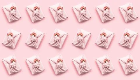 Holiday pattern present gift wrapped in a Furoshiki style cloth pink background Stock Photos