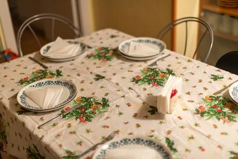 A holiday table is set with holly-patterned linens and plates. Stock Photos