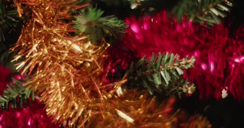 Holiday Tree Decorated with Glowing Lights and Festive Red and Gold Tinsel 库存影片 331105380