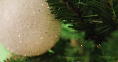 Holiday Tree Decoration Featuring a Sparkly White Ornament and Green Branches Vídeos de archivo 331105390