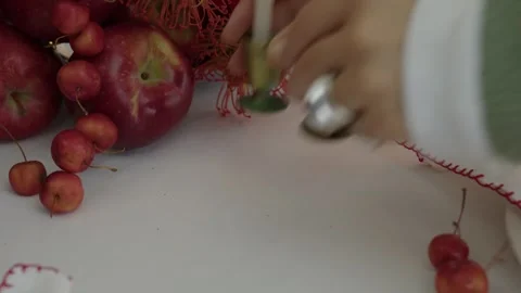 Holiday Warmth: Hands Set Candle Among Festive Apple and Berry Decor Stock Footage 259793718