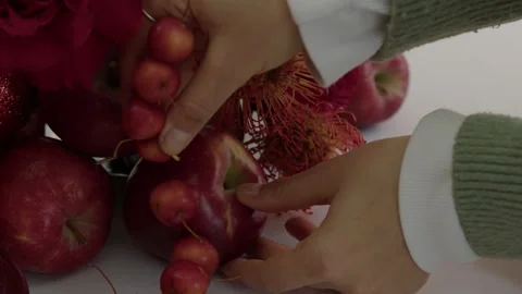 Holiday Warmth: Hands Set Candle Among Festive Apple and Berry Decor Stock Footage 259793735