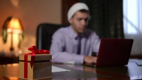 A Holiday Workspace featuring a wrapped gift alongside a laptop on a cozy desk Stock Footage 291541771