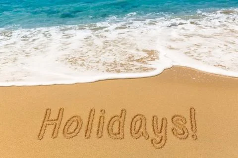 Holidays written in sand with sea surf Stock Photos