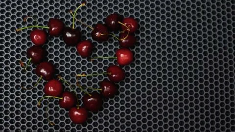 Hollow heart of red cherries close up from above against a dark background Stock Photos