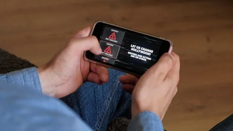 Hollywood On Strike Warning Message on Smartphone Screen in male hand Video stock 246491880
