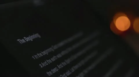 The Holy Bible on a tablet computer with lit candles in the background. Stock Footage 12389801