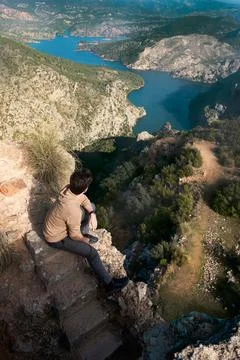 Hombre sentado en la montaña con un lago de fondo Stock Photos