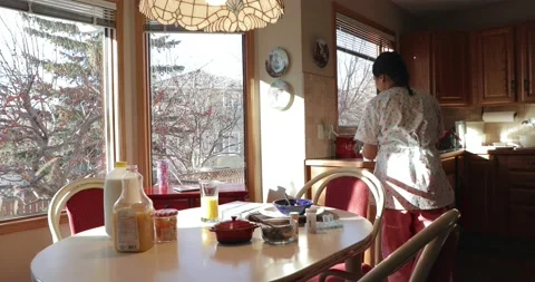 Home caregiver clearing breakfast table Video stock 220148888