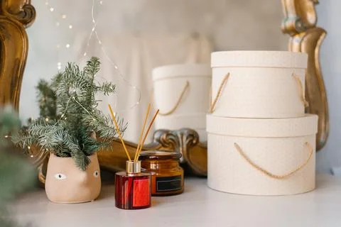 Home Christmas decor: diffuser, hat gift boxes, fir or spruce branches in a c Stock Photos