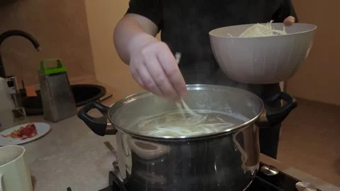 Home cook adding chopped cabbage to a boiling metal pot Stock Footage 342362899