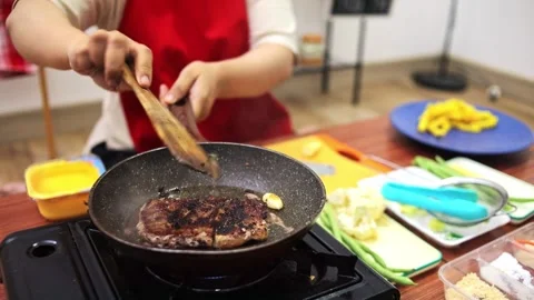 Home cook flipping searing beef steak in hot skillet with butter and garlic Stock Footage 345379492