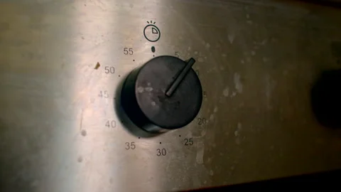 Home cook modifies time on scratched stainless steel oven knob Stock Footage 333906667