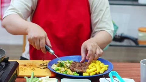Home cook Plating cooked beef steak with fries and vegetables with fresh herbs Stock Footage 345379898