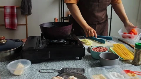 Home cook retrieving boiled tomatoes from pot and placing spaghetti into hot Stock Footage 345379500