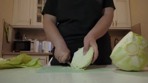 Home cook slicing cabbage into thin wedges on kitchen countertop Stock Footage 342362787