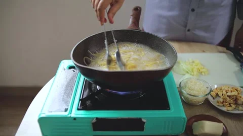 Home cook stirring and checking spaghetti boiling in bubbling hot water with Stock Footage 345376761
