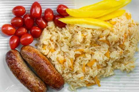 Home cooked lunch featuring rice, grilled sausage, tomatoes and paprika ser.. Stock Photos