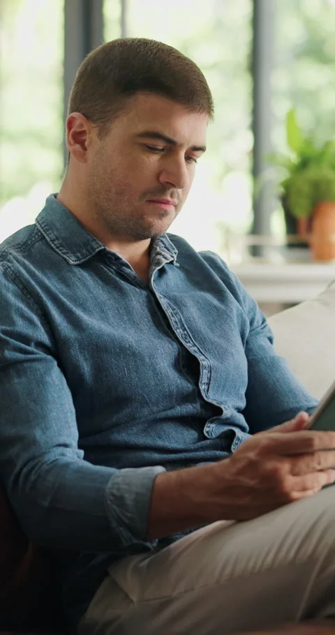Home, copywriting and man on sofa, tablet for online submission and editing for Stock Footage 330908480