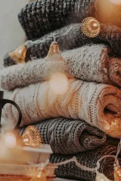 Home decor, sweaters, a stack of books and light bulbs, cozy winter interior  Stock Photos