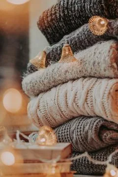 Home decor, sweaters, a stack of books and light bulbs, cozy winter interior  Stock Photos