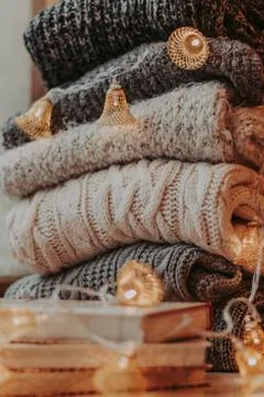 Home decor, sweaters, a stack of books and light bulbs, cozy winter interior  Foto stock