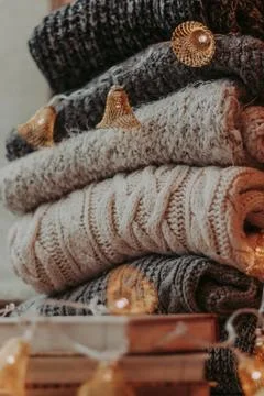 Home decor, sweaters, a stack of books and light bulbs, cozy winter interior  Stock Photos