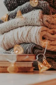 Home decor, sweaters, a stack of books and light bulbs, cozy winter interior  Foto stock