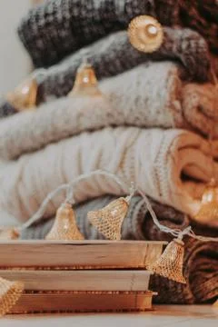 Home decor, sweaters, a stack of books and light bulbs, cozy winter interior  Stock Photos