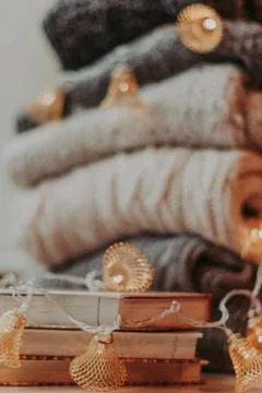 Home decor, sweaters, a stack of books and light bulbs, cozy winter interior  Stock Photos
