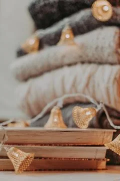 Home decor, sweaters, a stack of books and light bulbs, cozy winter interior  Stock-Fotos